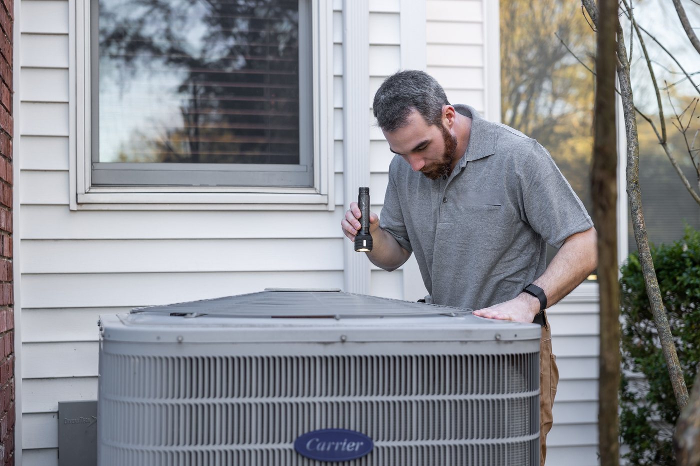 Technician inspecting a residential outdoor air conditioning unit