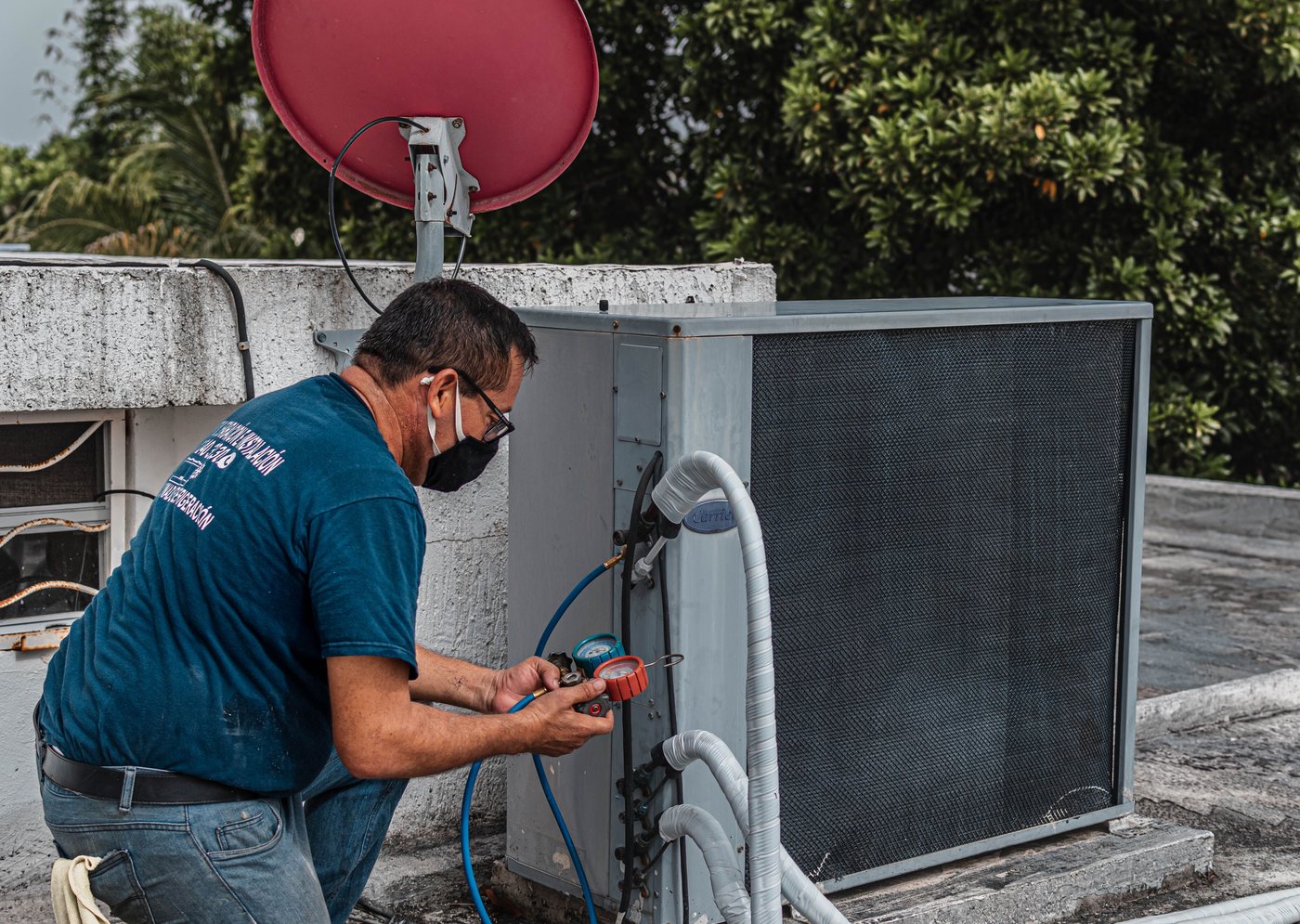 Technician repairing an outdoor air conditioning unit with pressure gauges
